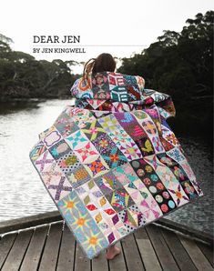 a woman is standing on a dock holding a quilt