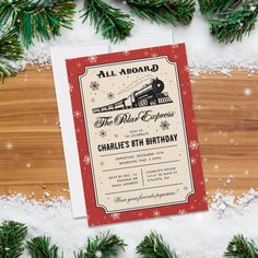 an old fashioned christmas card with snow and pine branches around it on a wooden surface