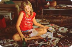 a young woman sitting on the floor surrounded by magazines and other items in her living room