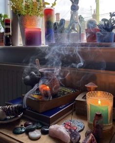 a table with candles, rocks and other items on it in front of a window