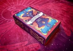 a card game box sitting on top of a pink blanket with an image of a dragon