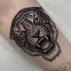 a black and white tiger tattoo on the right arm, with its mouth wide open