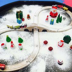 a toy train set in the snow with santa and other toys on it's tracks