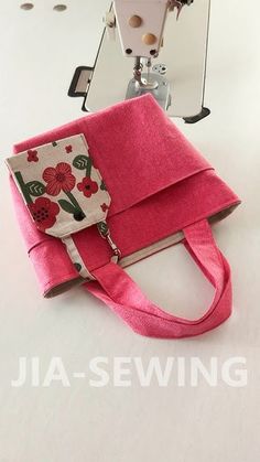 a pink purse sitting next to a sewing machine