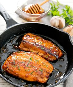 two pieces of meat in a skillet with garlic and parsley on the side