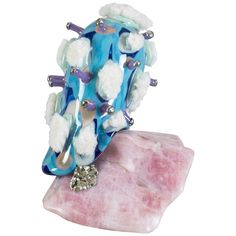 a blue and white brooch sitting on top of a pink rock