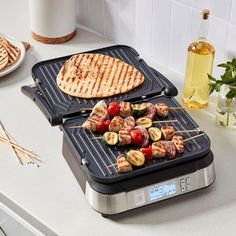 two panini grills with skewered vegetables and meat on them sitting on a kitchen counter