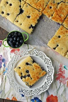 blueberry bars on a white plate next to a bowl of blackberries