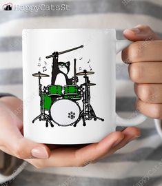 a person holding a coffee mug with a drum set on it