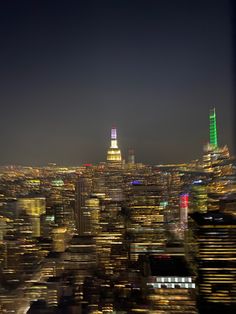 an aerial view of the city at night with lights on and buildings lit up in bright colors