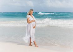 a pregnant woman is standing on the beach