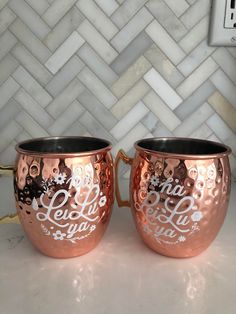 two copper mugs sitting on top of a counter