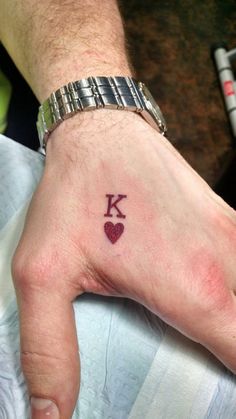 a person's left hand with a small tattoo on the middle finger and heart