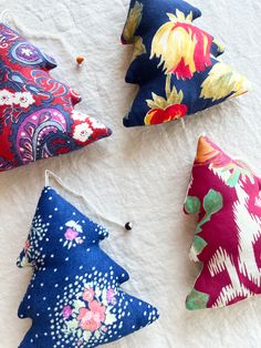 four different colored pillows sitting on top of a white sheet next to an orange and blue flowered ornament