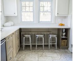 three stools are in the middle of a kitchen with white cabinets and tile flooring