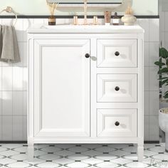 a white bathroom vanity sitting under a mirror next to a potted plant and sink