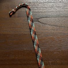 an orange, blue and black braided lanyard on top of a wooden table