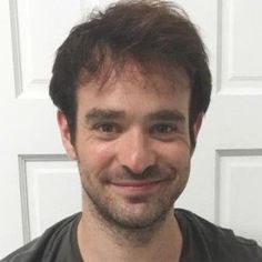 a man smiling for the camera in front of a white door