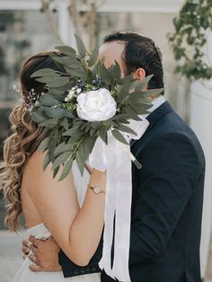 a bride and groom embracing each other with flowers in their hair