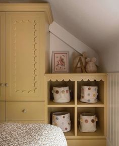 a bed sitting under a window next to a shelf filled with pillows and other items