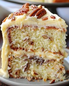 a slice of cake with white frosting and pecans on top