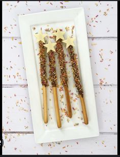 three wooden stars on top of some sprinkles in a white square plate