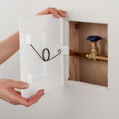 a person opening a hole in the wall with a water faucet attached to it