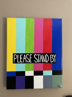 there is a sign that says please stand by on the side of a wall with different colors