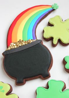 decorated cookies with shamrocks, rainbow and pot of gold on white tablecloth for st patrick's day