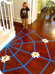 a young boy standing in the middle of a room with blue tape on the floor