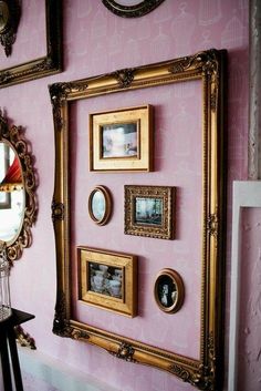 there are many pictures on the wall in this room with pink walls and gold frames