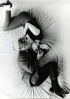 black and white photograph of two people laying on a bed with one holding a cell phone