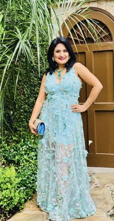 a woman standing in front of a door wearing a blue dress and holding a purse