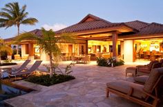 an outdoor living room and dining area with palm trees in the background at night time