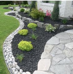 a garden with rocks and grass in front of a house