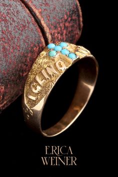 a gold ring with turquoise stones on it and the words africa written in cursive writing