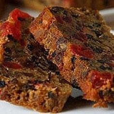 two pieces of fruitcake on a plate with another piece in the foreground and one half eaten