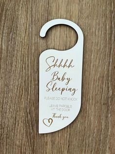 a white wooden door hanger with the words, baby sleeping please do not knock leave parcel