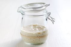 a glass jar filled with food sitting on top of a white table next to a spoon