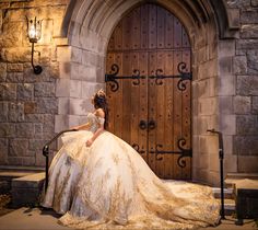 a woman in a wedding dress is sitting on a bench outside an old castle door