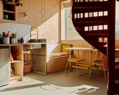 a kitchen with a spiral staircase next to a table and chairs in front of a window