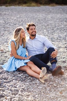 a man and woman are sitting on the ground smiling at each other while they both have their arms around each other