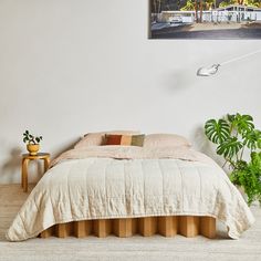 a bed sitting next to a plant in a bedroom