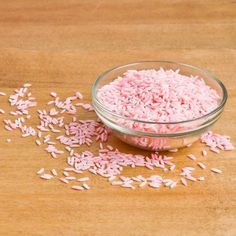 pink sprinkles in a glass bowl on a wooden table