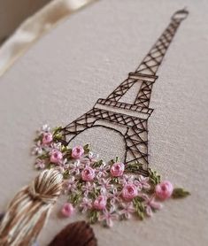 a cross stitched picture of the eiffel tower with pink flowers on it