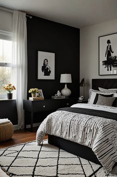 a black and white bedroom with pictures on the wall above the bed, along with an area rug