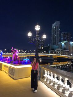 a woman is standing on a bridge at night