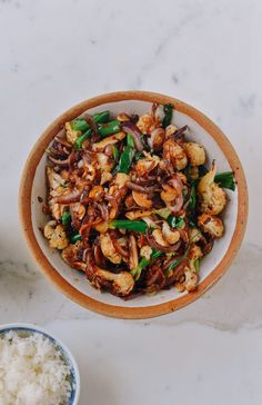 a bowl filled with stir fried vegetables and rice next to a small bowl of seasoning