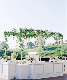 an outdoor wedding setup with white furniture and greenery