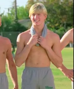 three young men standing next to each other in front of a soccer field wearing towels